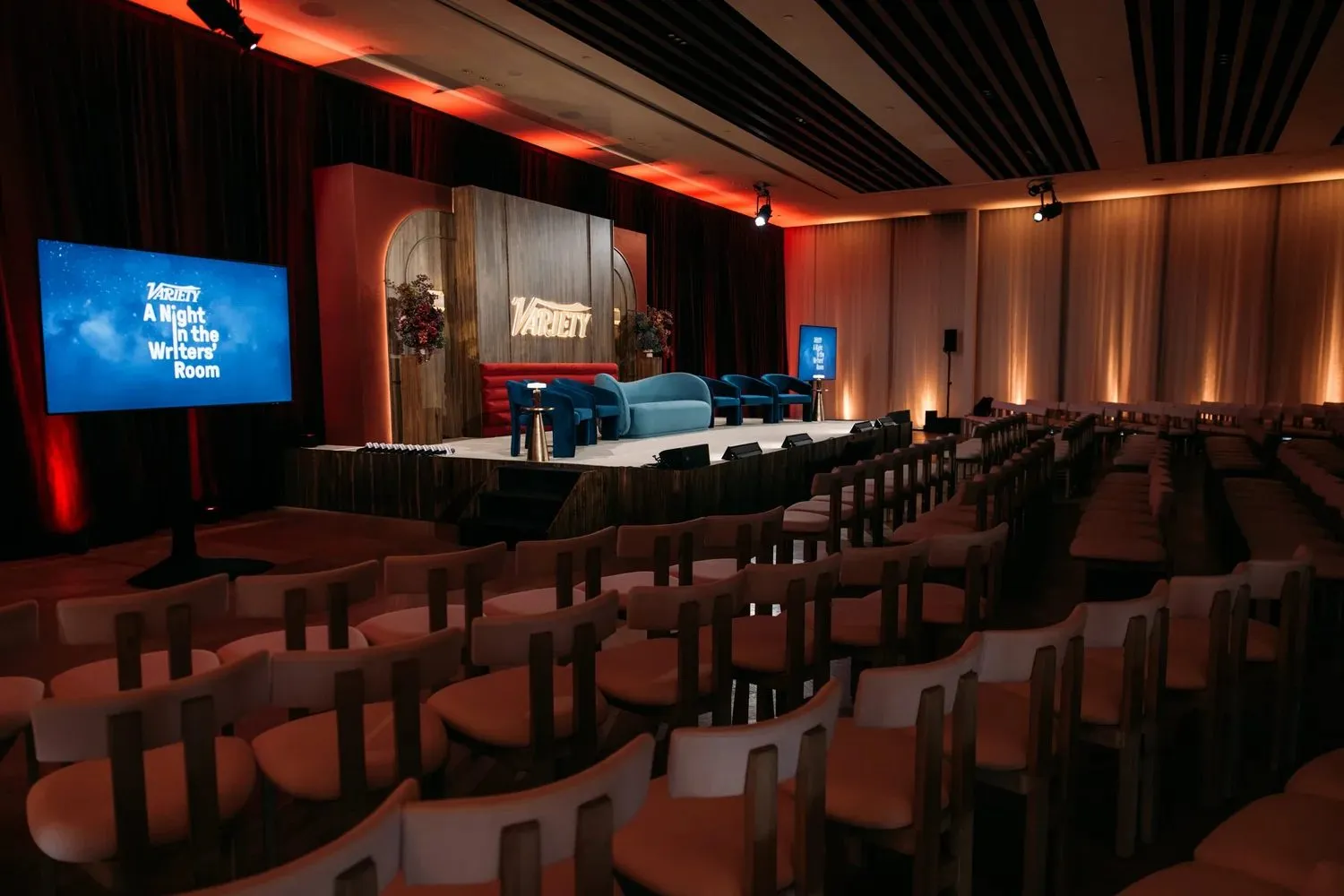 Event hall with rows of seating facing a stage and screens