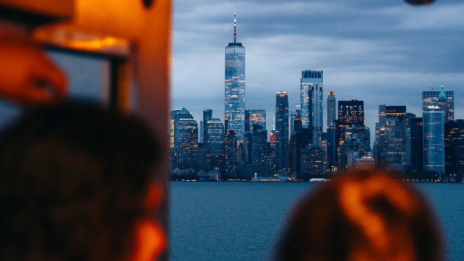Two guests on a boat watch the Lower Manhattan skyline glow at dusk during an incentive trip in New York.