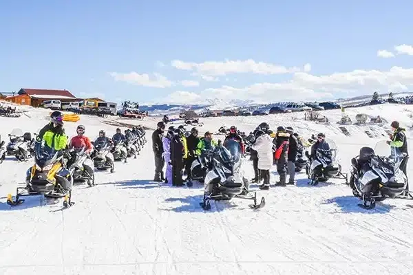 Group snowmobile outing lined up on a snowy ridge