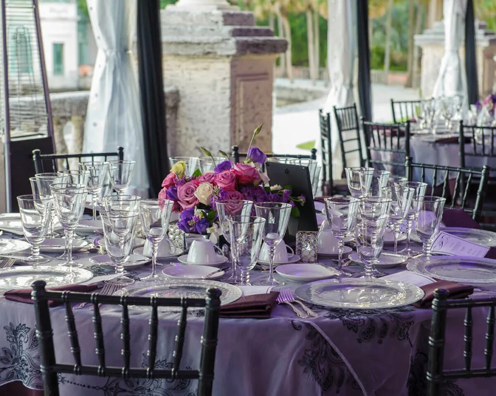 Dinner table with purple flowers and glassware set outdoors at a Miami venue