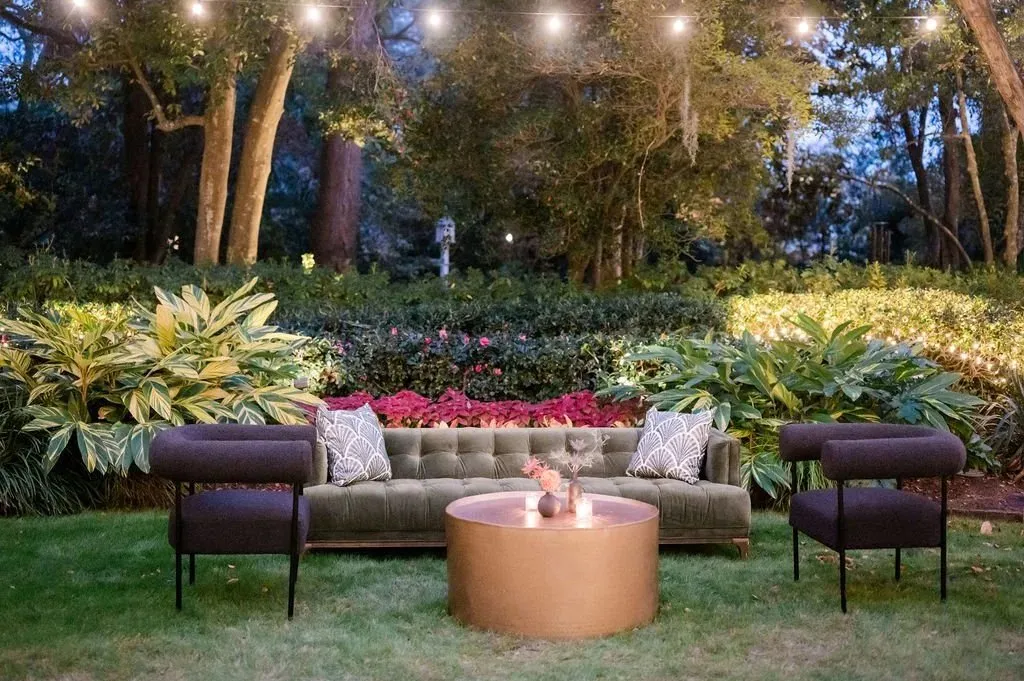 Garden lounge with sofas around a fire table and string lights