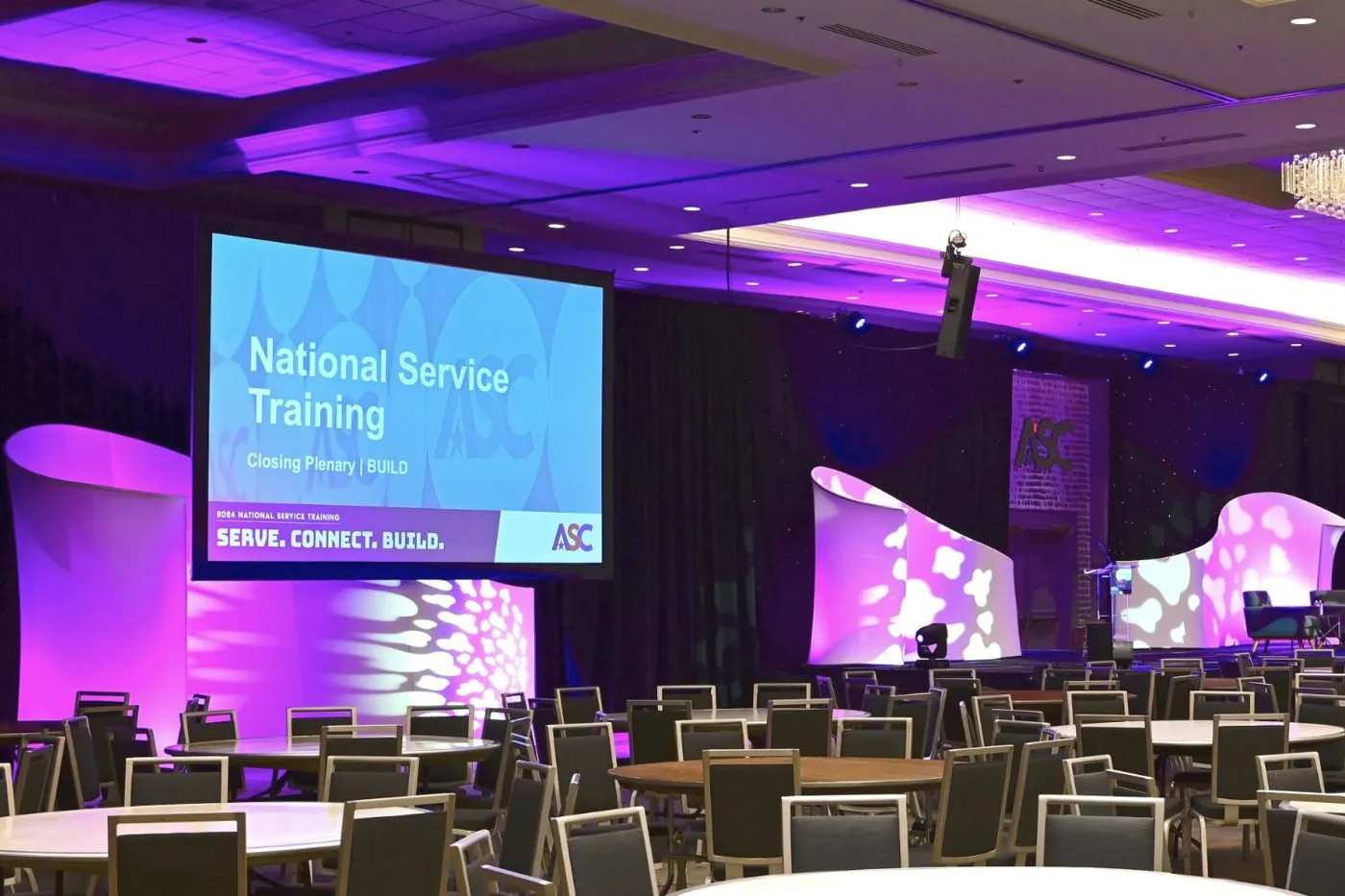 General session stage lit in purple with a projection screen and theater seating