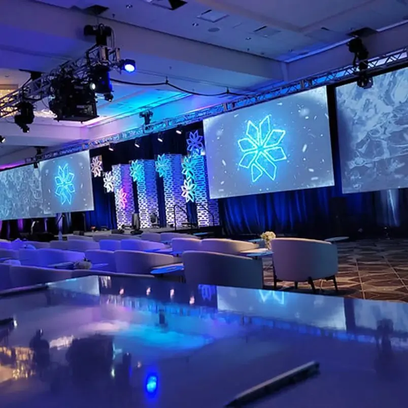 Ballroom with large screens and stage lighting set for a corporate event