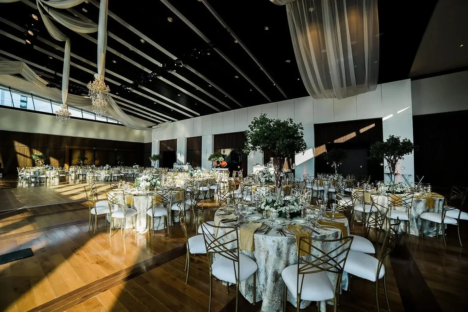 Round dinner tables with cream linens set inside a large event hall
