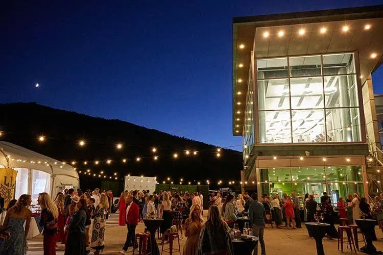 Evening reception under string lights with mountains behind