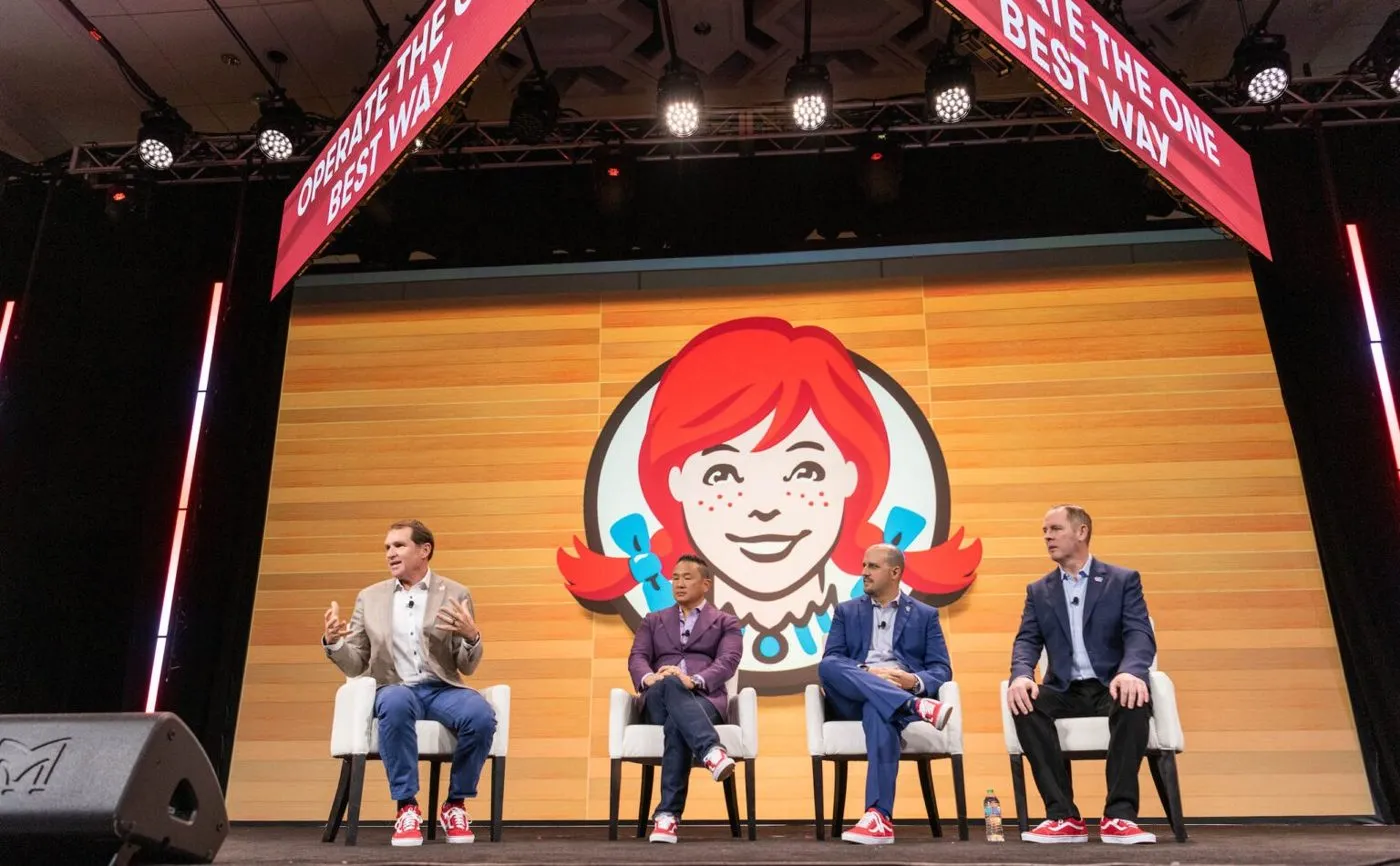 Panel discussion on a conference stage in front of a large backdrop