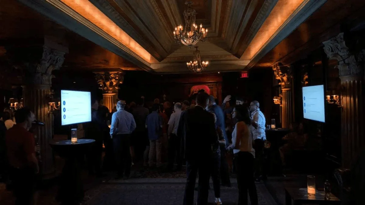 Guests gathered in a dark paneled room with presentation screens