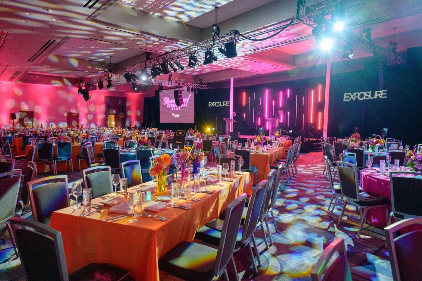 Gala dinner tables with pink stage lighting in a ballroom