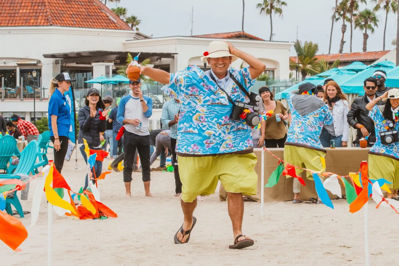 Participant in a bright shirt guiding a beach team activity under flags