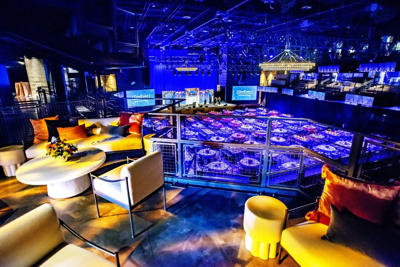 Large blue-lit event hall with lounge seating and banquet tables