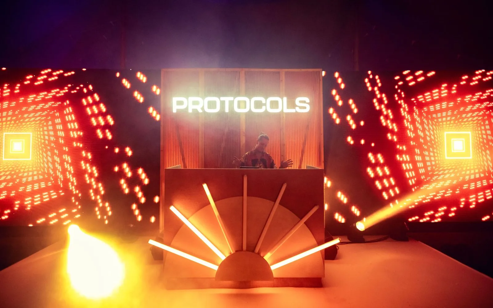 Conference stage with a glowing cube set piece and a lit logo sign