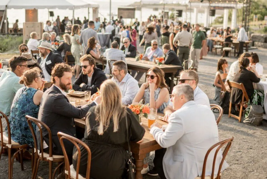 Guests at long outdoor dining tables on a sunny patio
