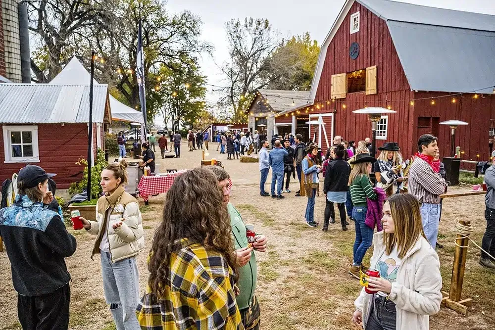 Guests mingling at an outdoor event beside a red barn