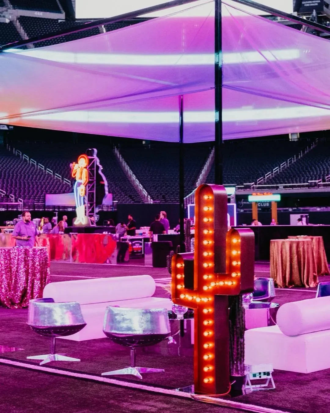 Arena event with lounge seating, a lit cactus sign and a draped canopy