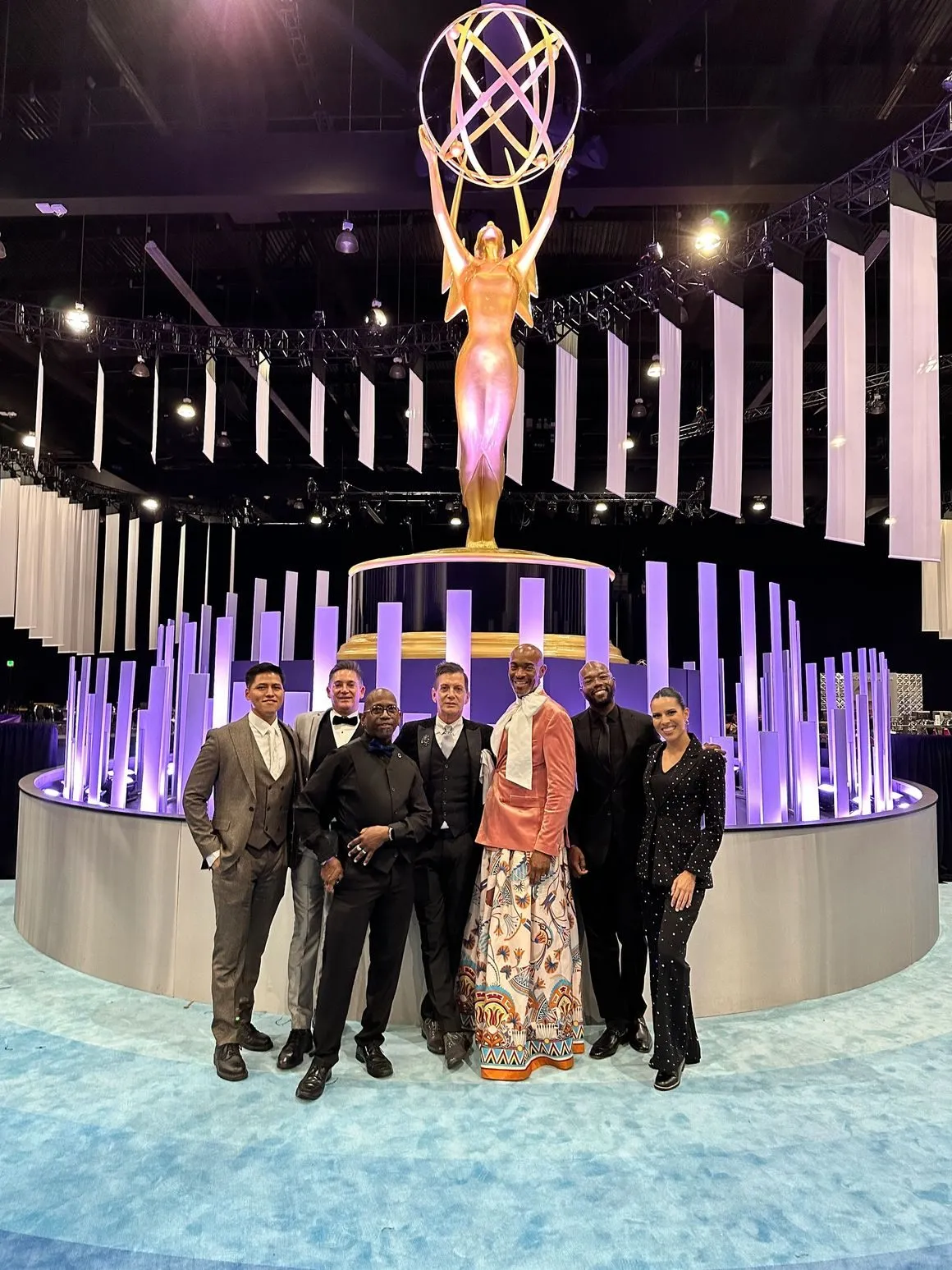 Group standing near a large statue and a lit fountain at a staged event