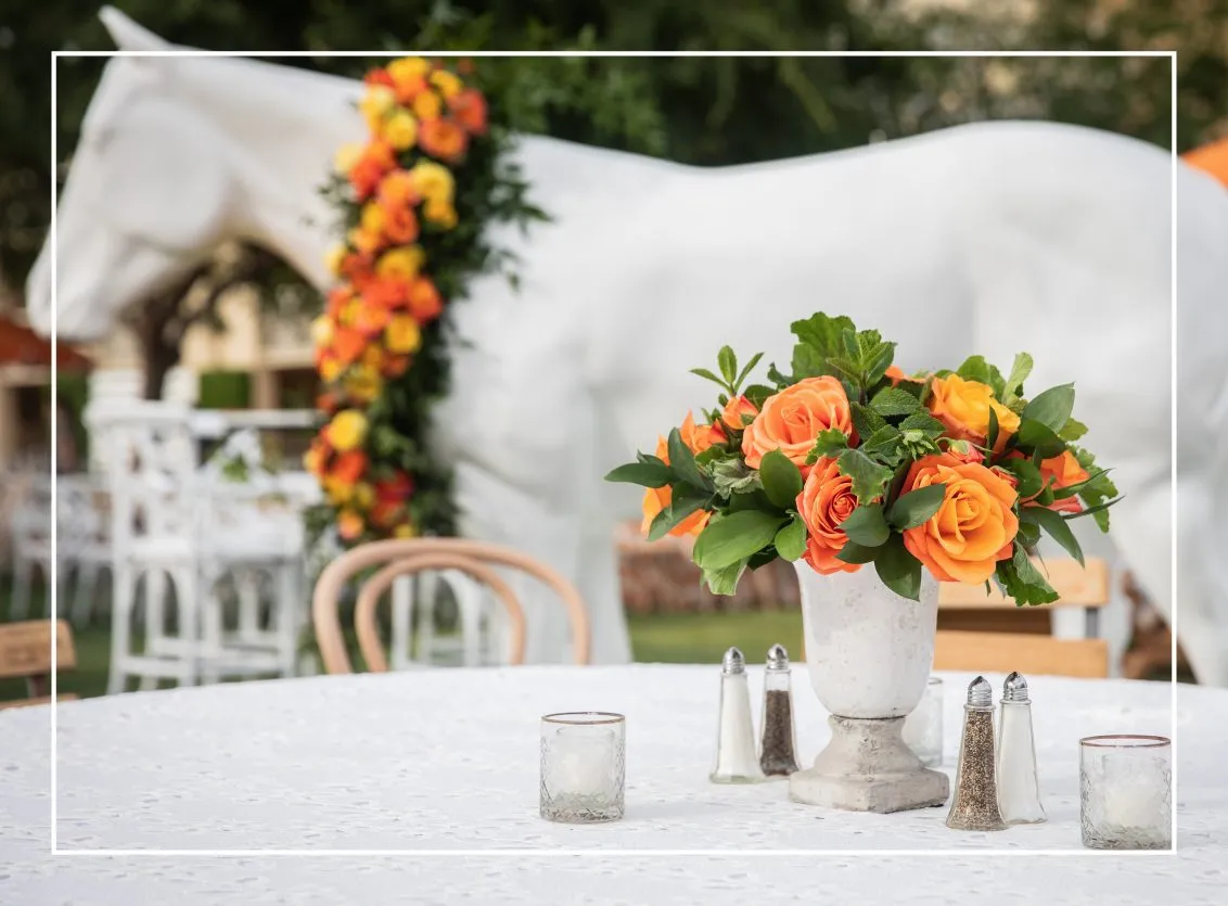 Table with orange florals and a white horse sculpture as decor