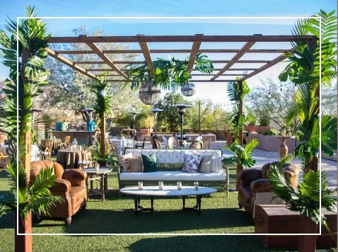 Pergola lounge with sofas and plants set up on a lawn