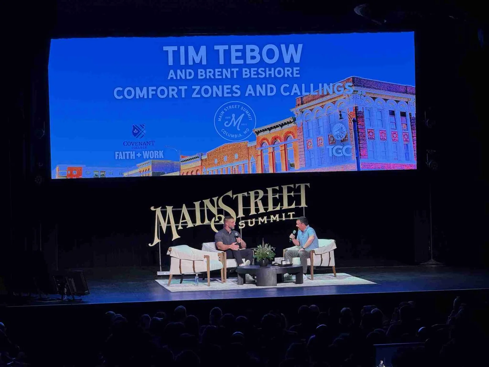 Stage with two speakers seated in front of a large MainStreet Summit screen
