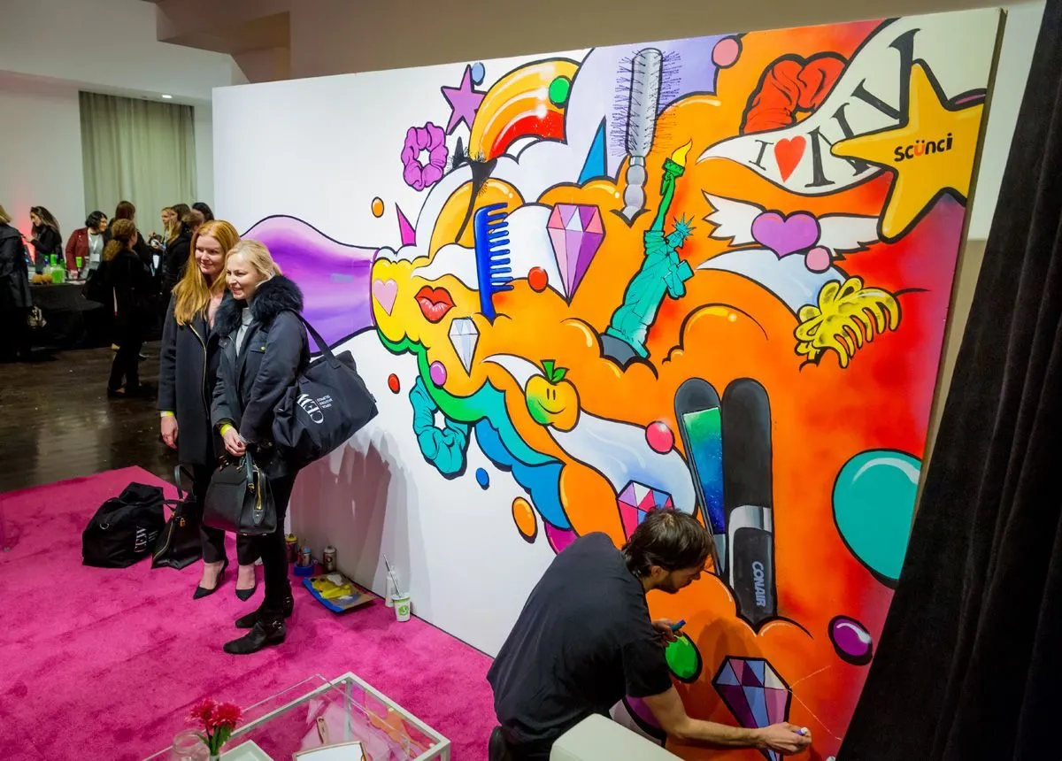 Artist painting a colorful live mural as guests watch at an activation