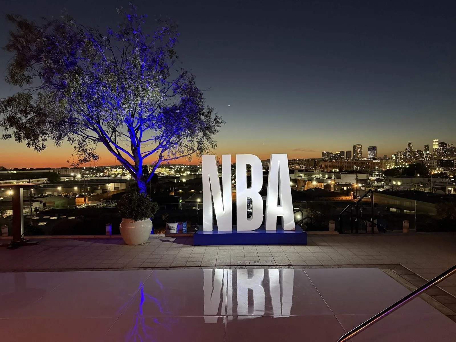 NBA letters lit on a rooftop terrace at dusk during an NBA All-Star sponsor event