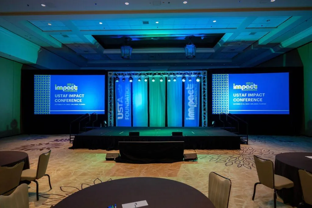 Conference ballroom with a staged general session set and three wide screens