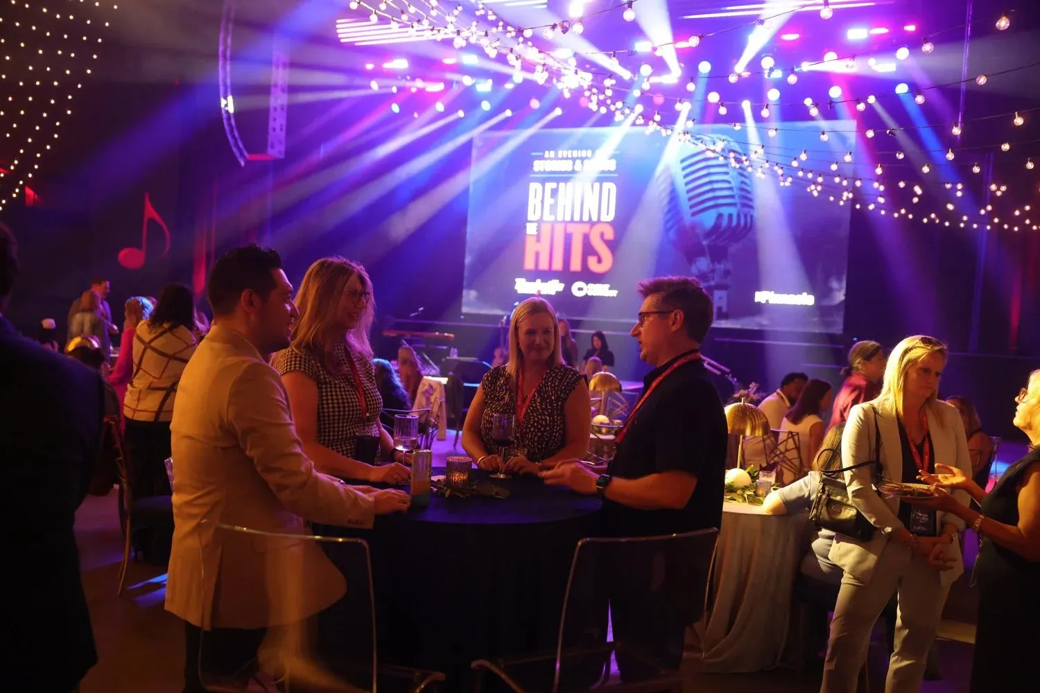 Guests seated at tables facing a lit stage during a company event