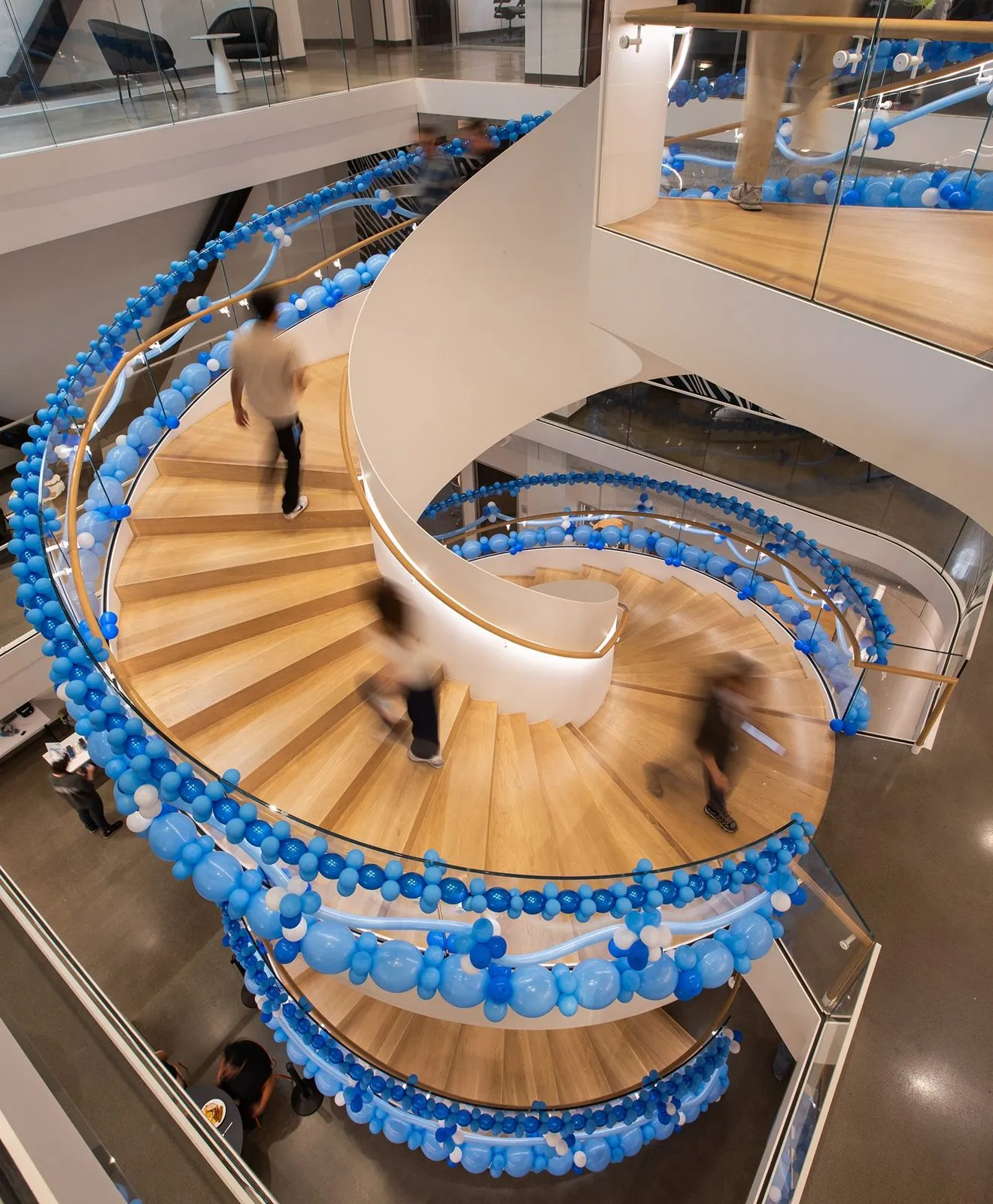 Spiral staircase in an office atrium decorated with blue balloons for an anniversary celebration