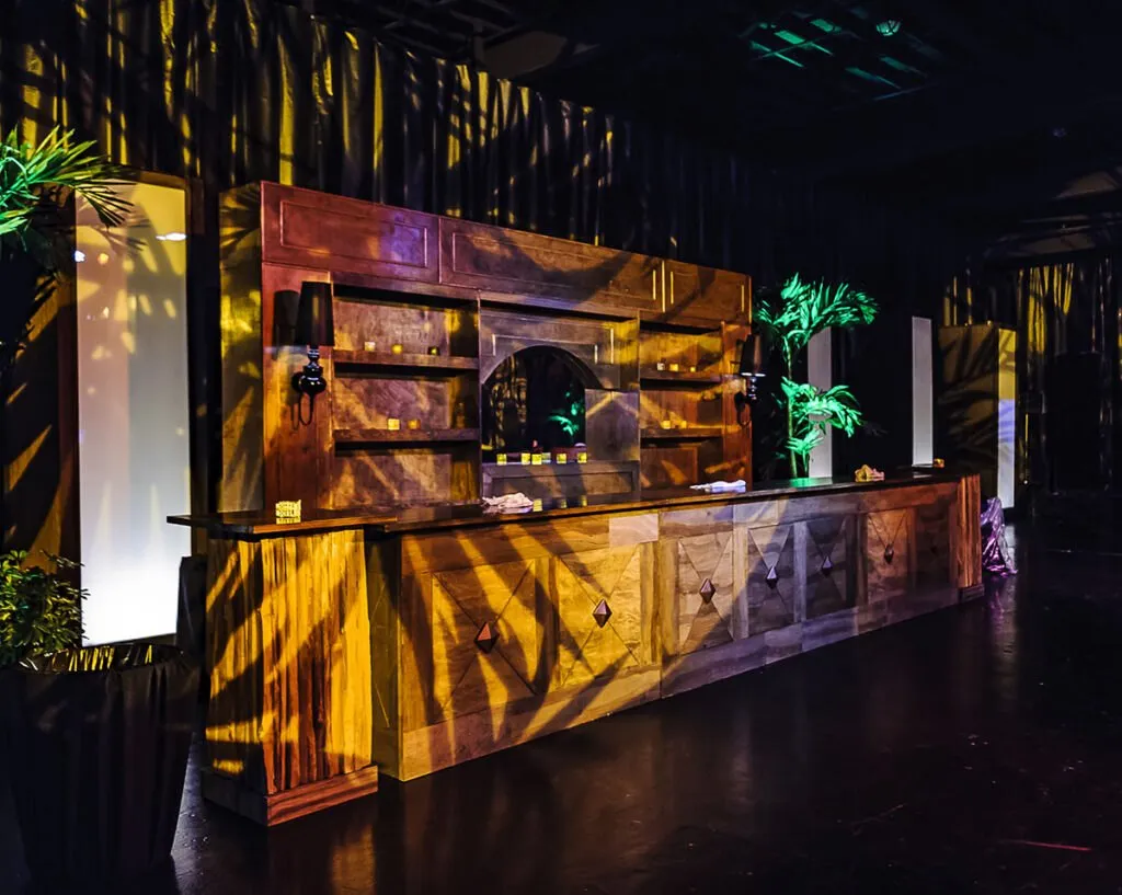 Lit bar with tropical foliage shadows set up for a Havana Nights themed event