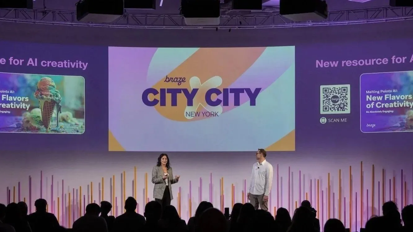 Two presenters on stage in front of an audience at a company summit
