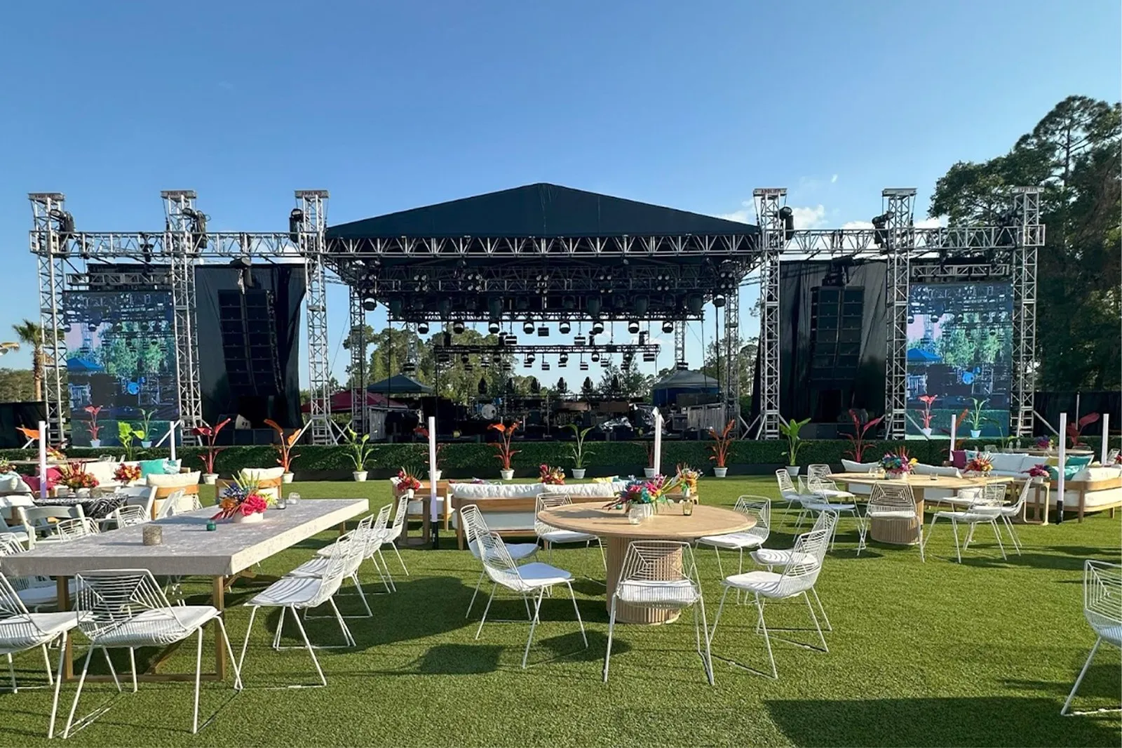 Outdoor stage and dining tables set on a lawn for a company event