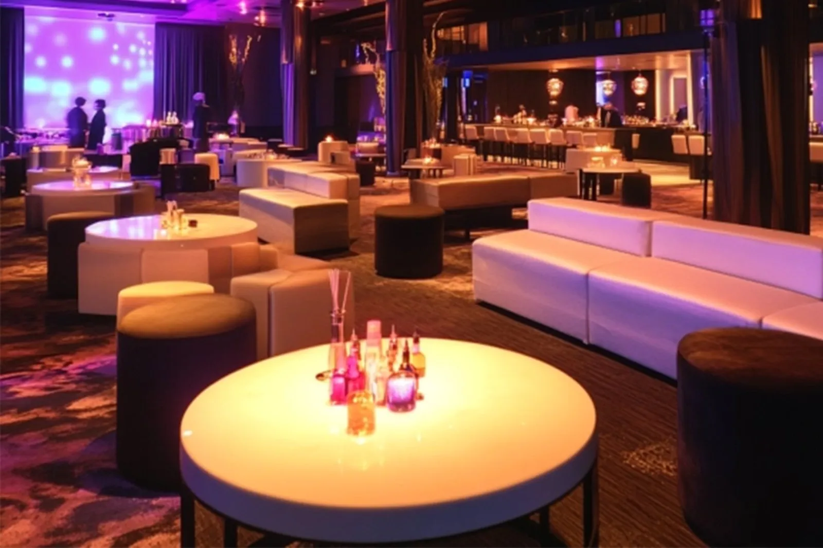 Lit cocktail tables and white lounge seating for an evening event