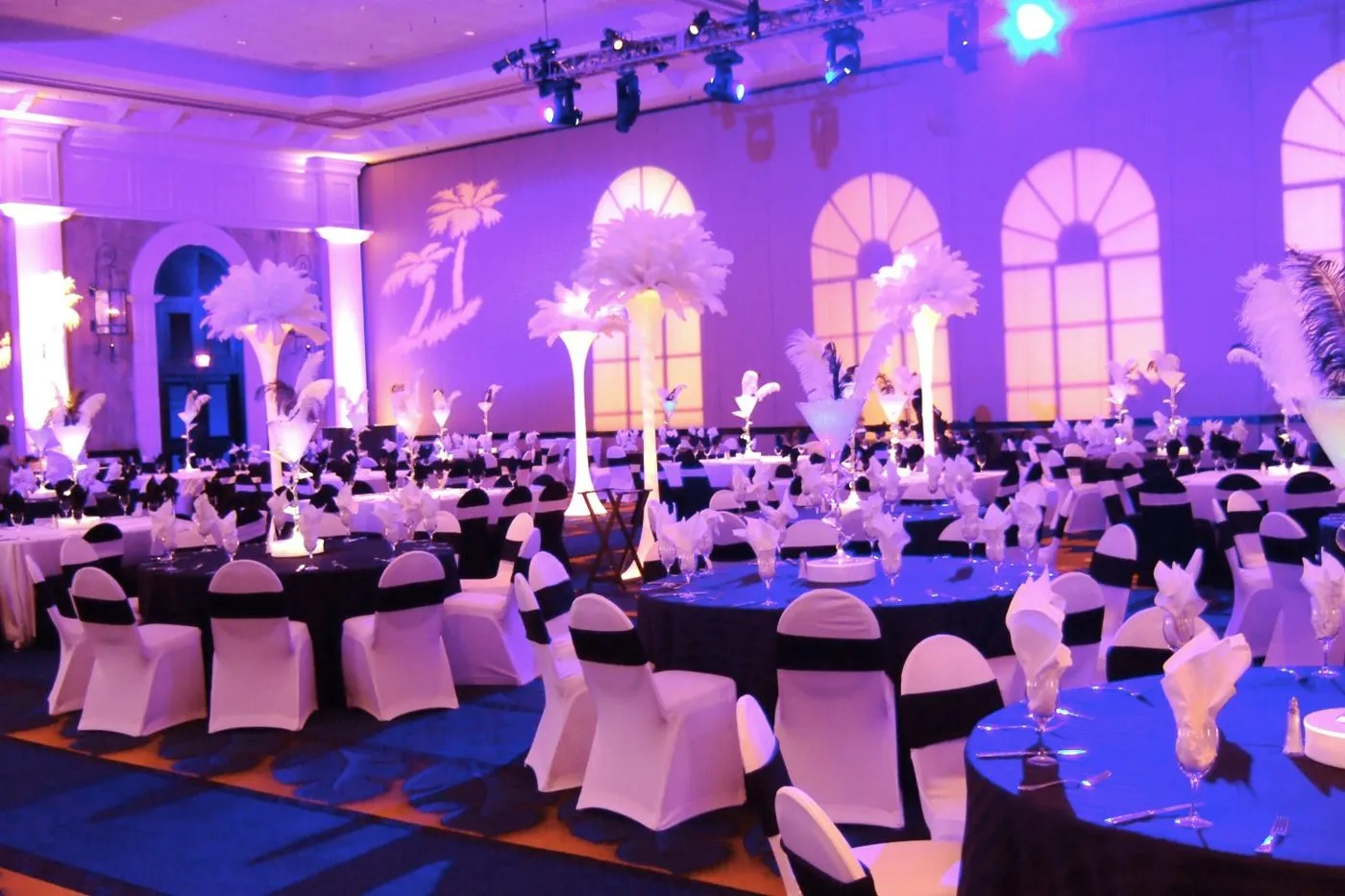 Gala ballroom with round tables, uplighting and chandeliers