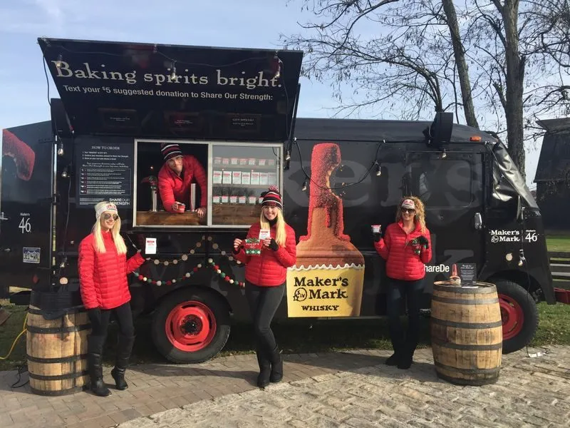 Branded truck activation with staff in red jackets beside barrels