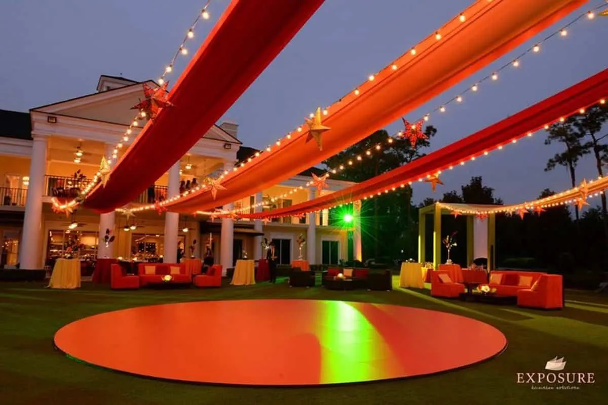 Carnival themed lawn event with red draped tents and a round lit dance floor