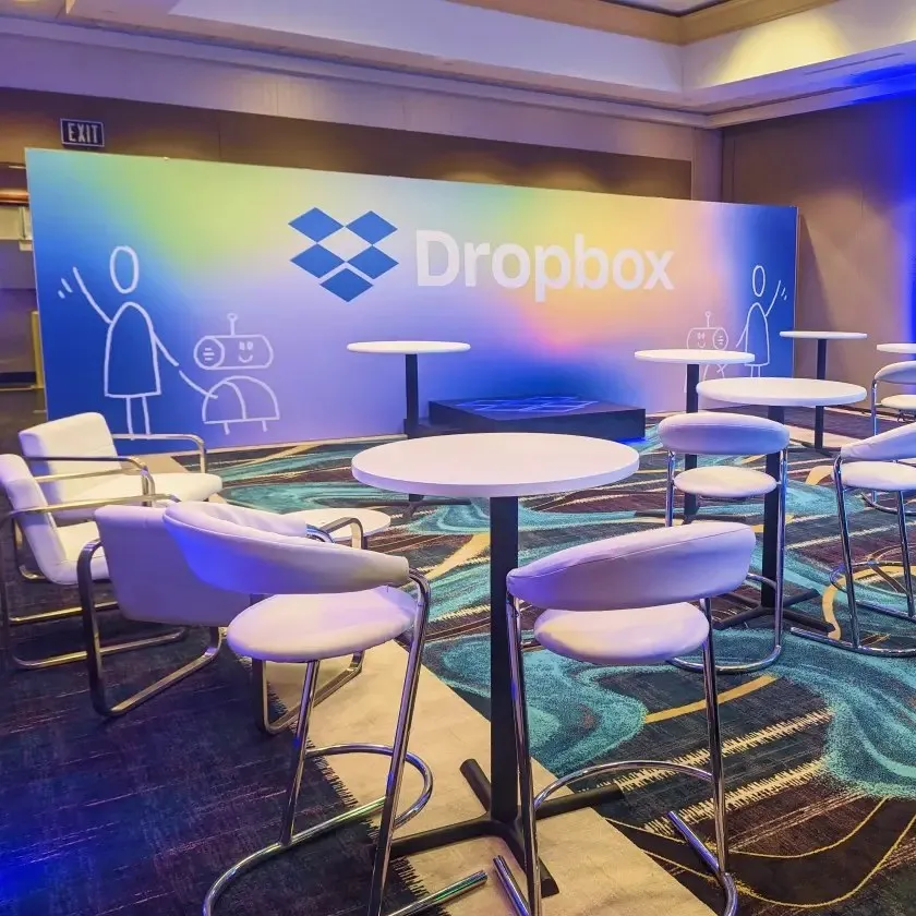 Dropbox-branded lounge with white seating and a printed backdrop
