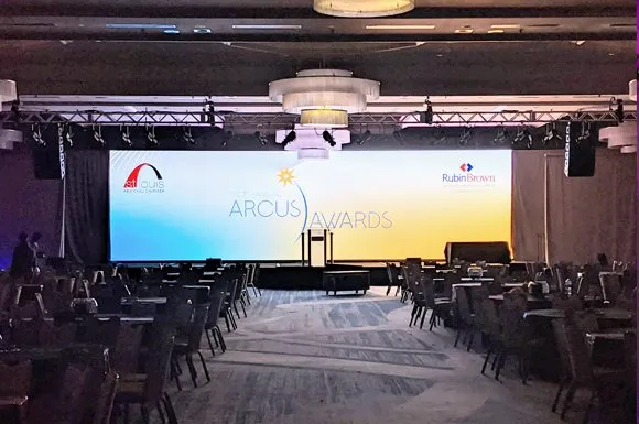 Stage with a wide screen set in front of rows of tables
