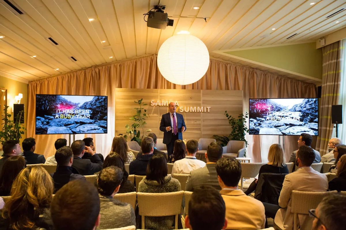 Speaker presenting to a seated audience at a corporate summit