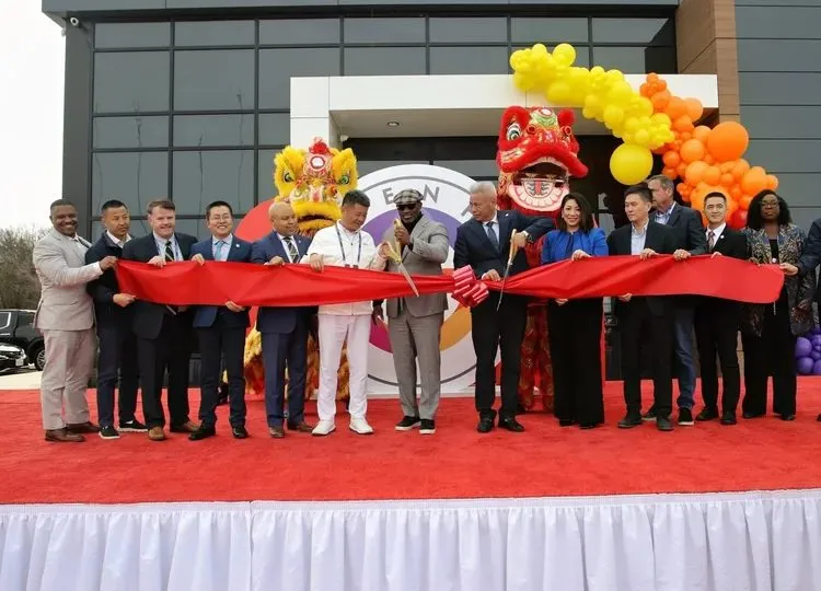 Ribbon cutting ceremony with yellow and orange balloons at a company opening