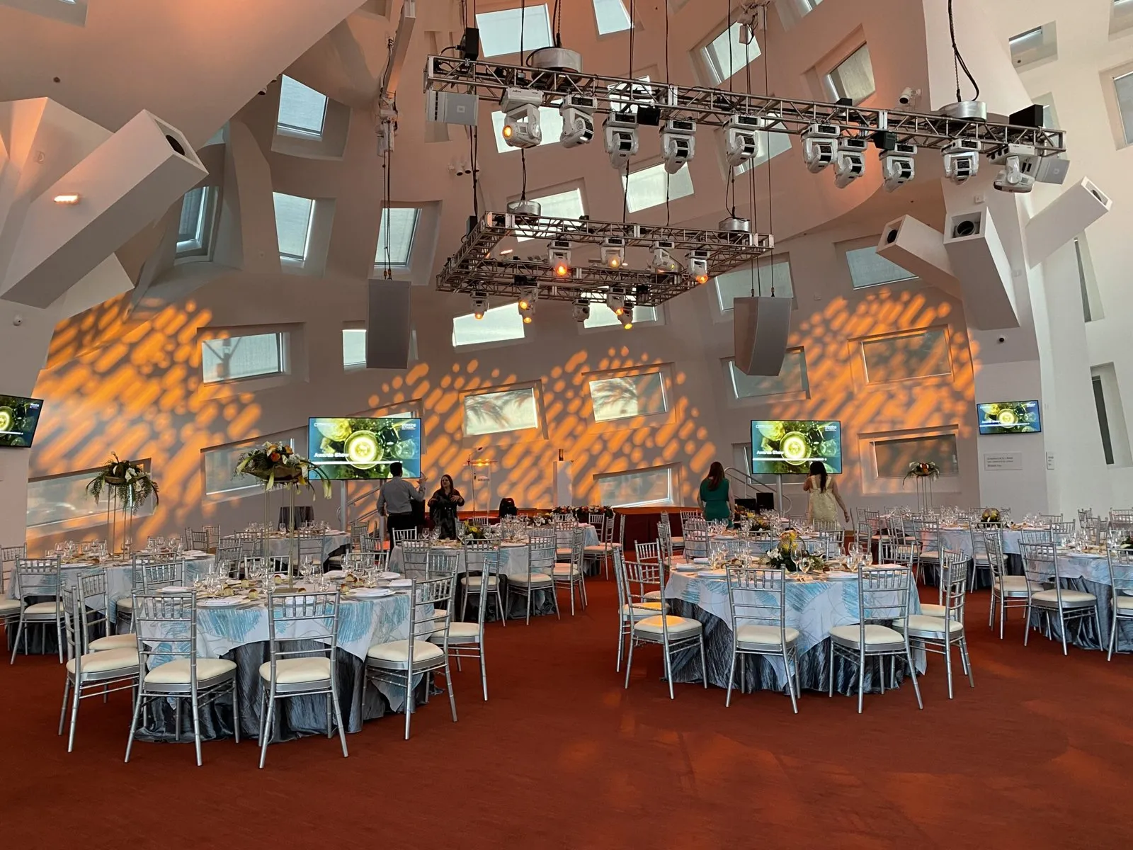 Dinner tables under a sculpted ceiling with gobo lighting