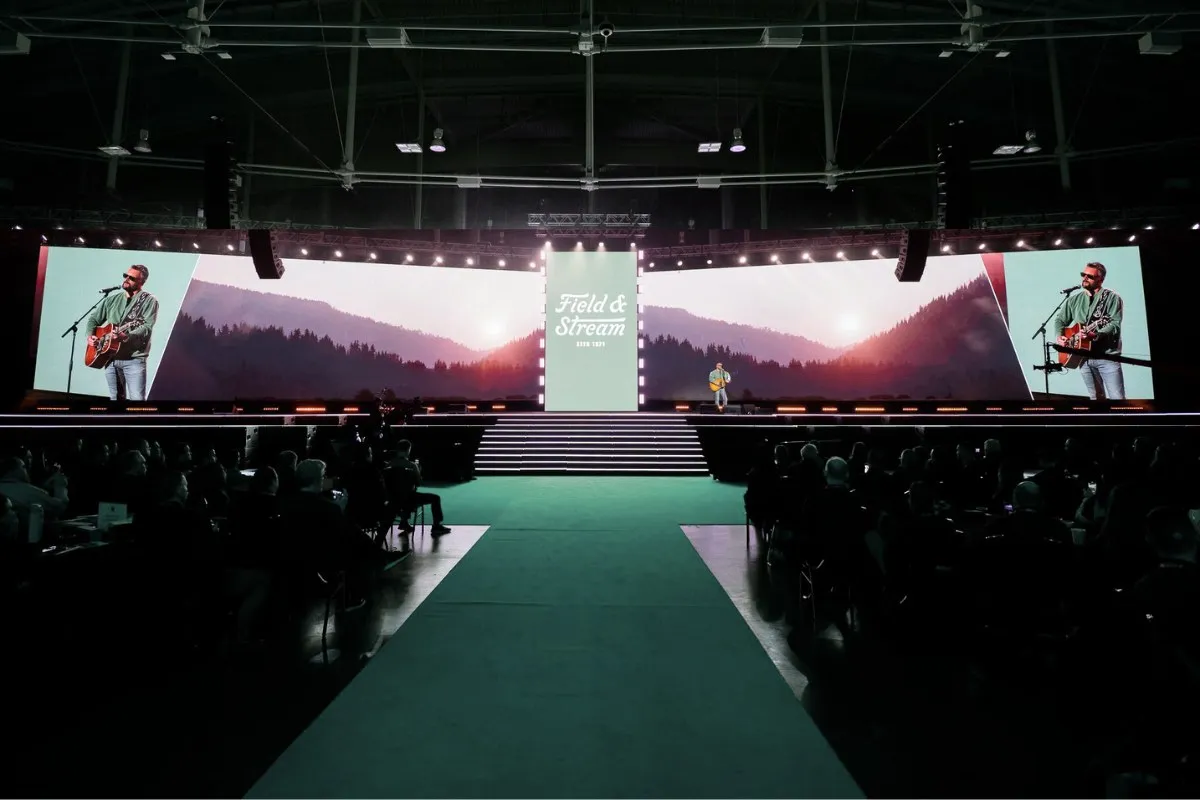 Stage framed by wide screens with a green runway down the center