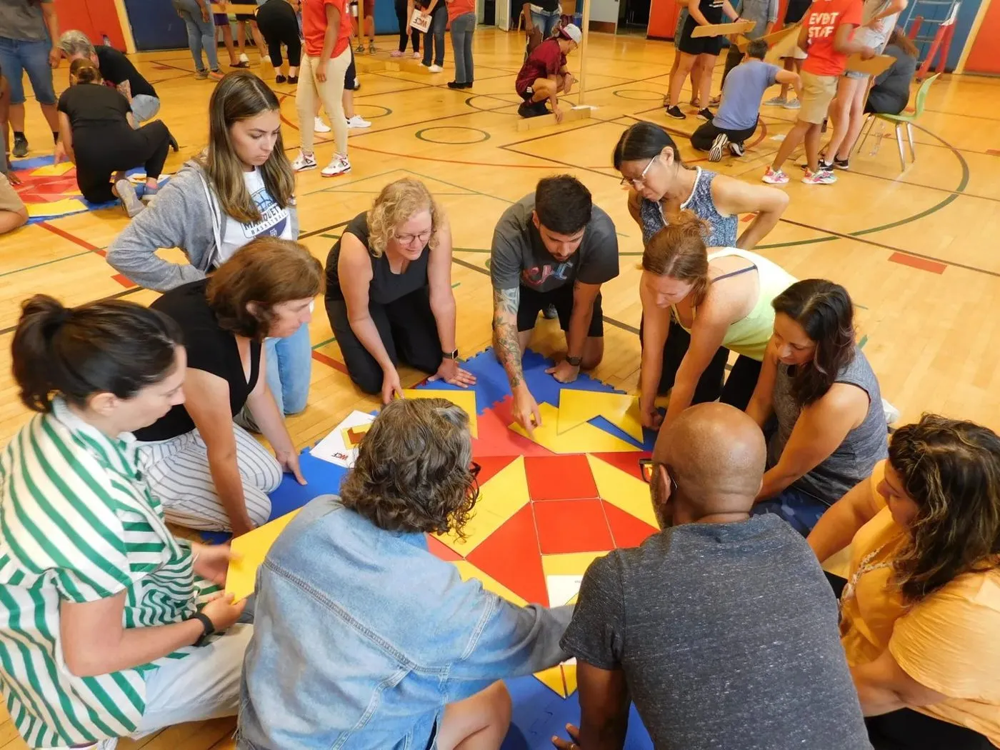 Team members playing a floor game in a gym during a team building event