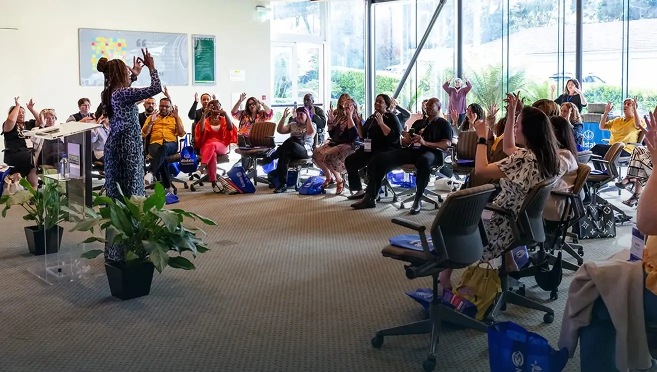 Attendees seated in a circle during a workshop session in a bright meeting space
