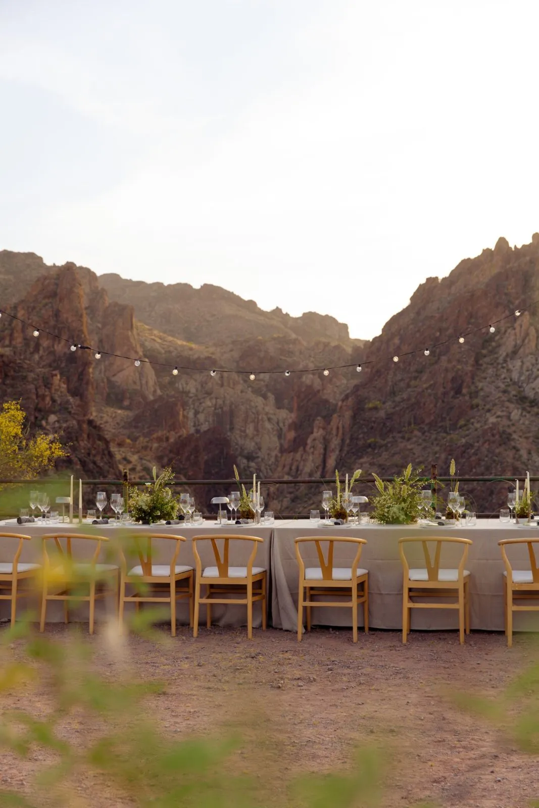 Terrace dinner tables under string lights with desert canyon walls beyond