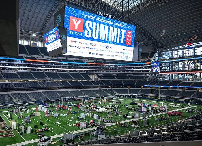 Summit event set up on the field of a football stadium with large video boards
