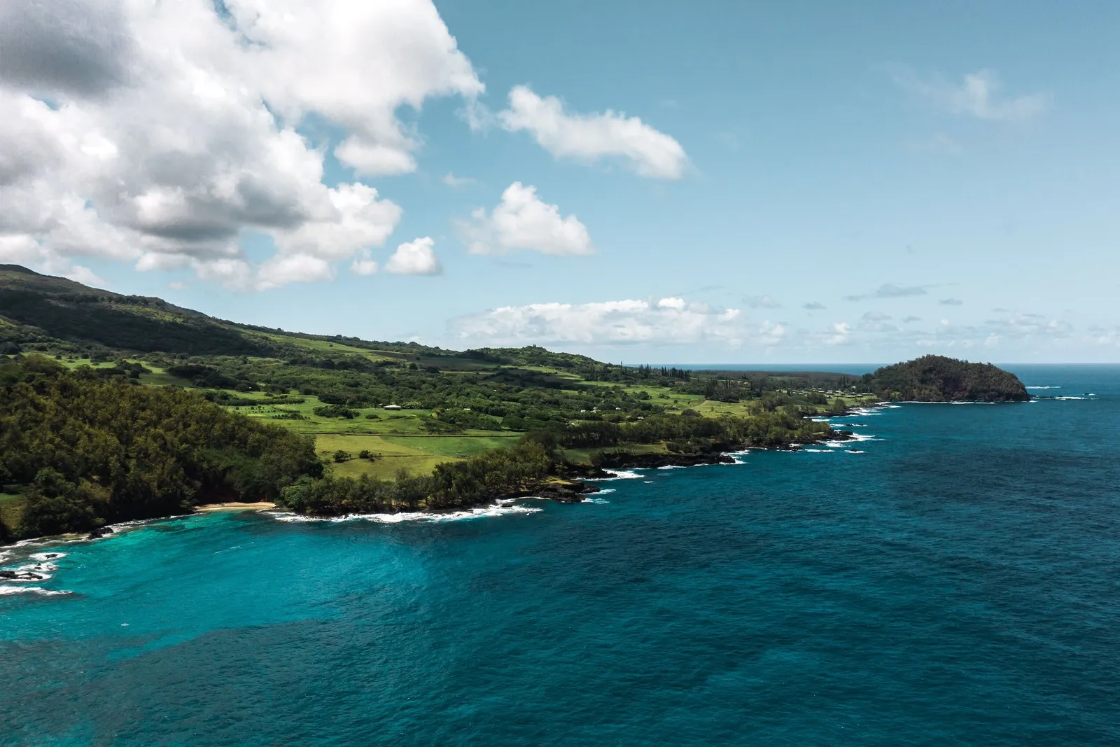 Green hills and lava rock on the coast near Hāna, Maui.