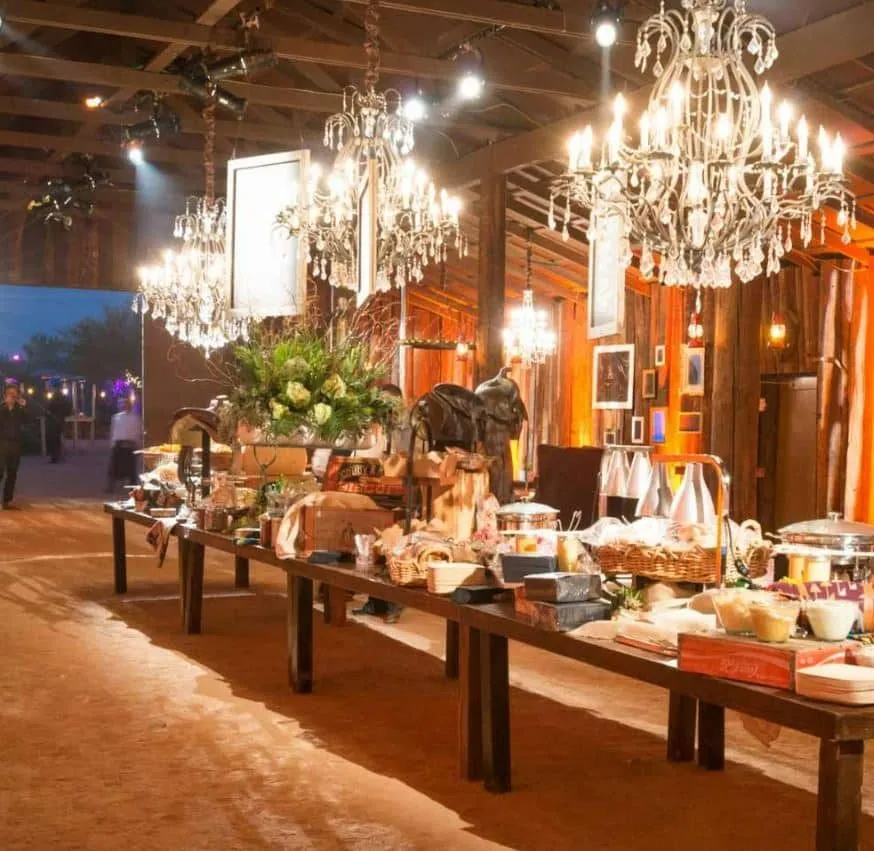 Long buffet tables under chandeliers in a rustic event hall