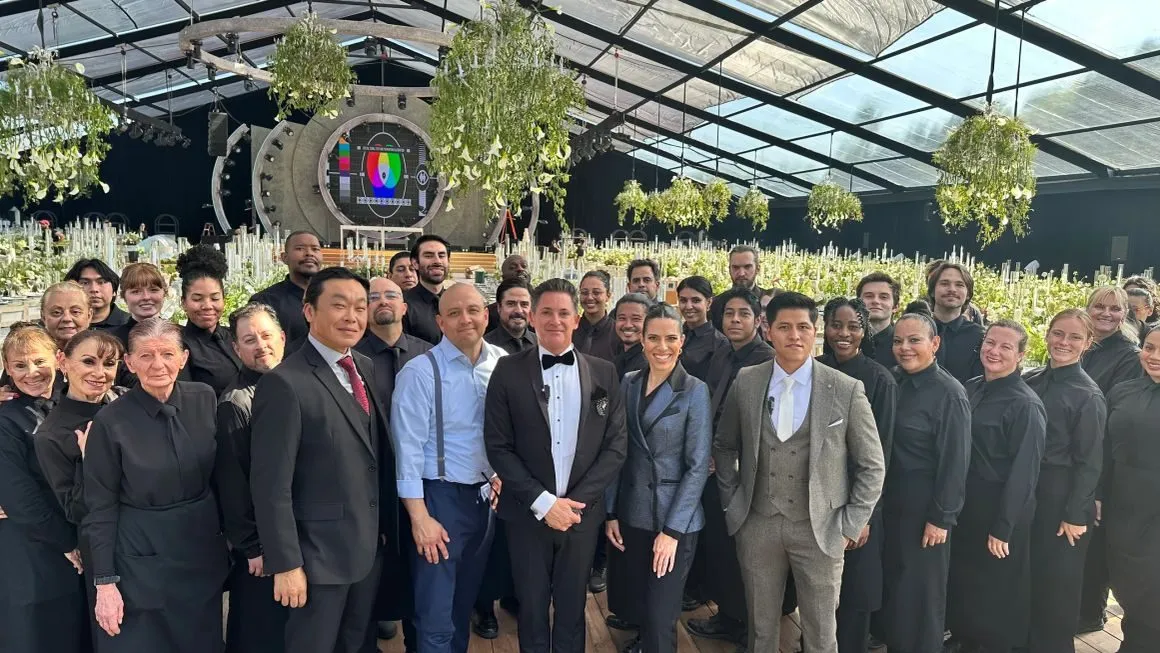 Large hospitality team lined up inside a glass roofed tent at an event