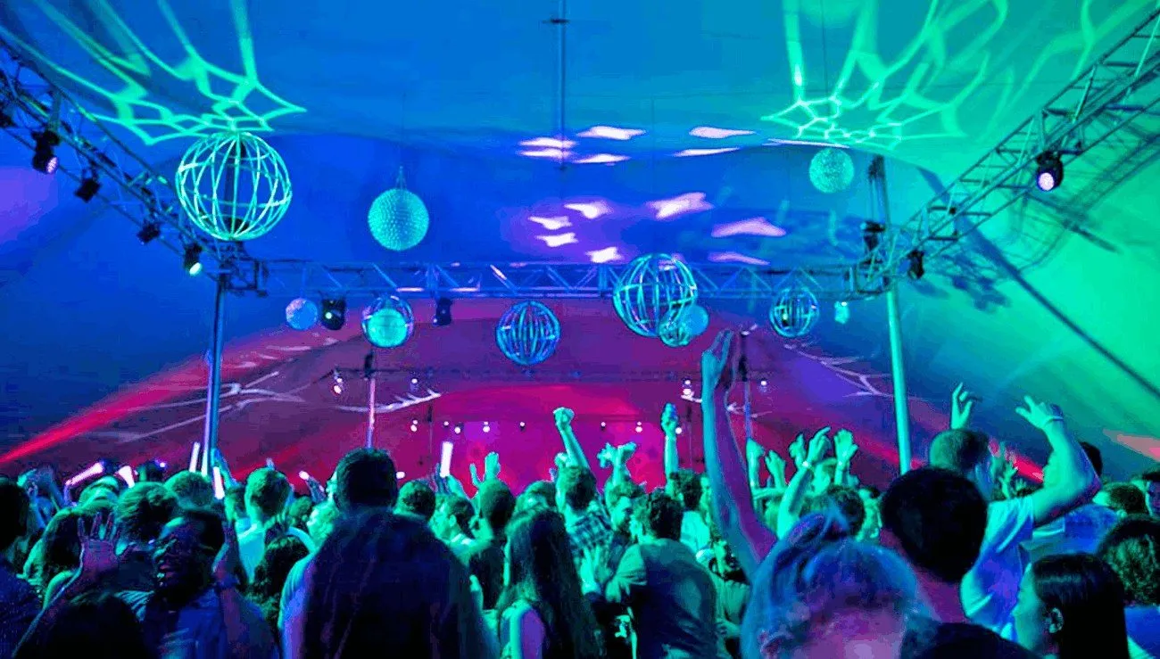 Guests dancing under blue and green lights at a large company party