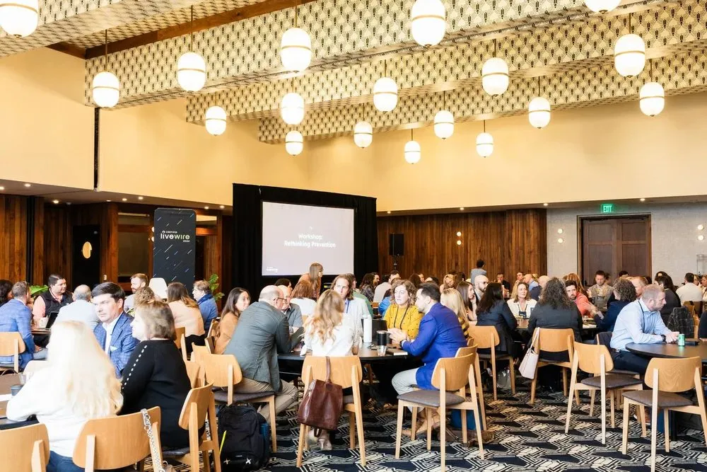 Attendees seated at round tables in a hotel ballroom at a customer summit