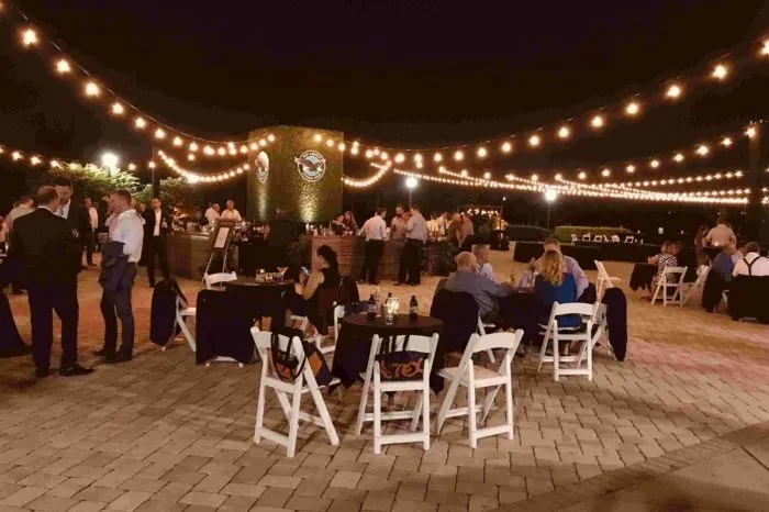 Guests at tables under string lights on an evening patio